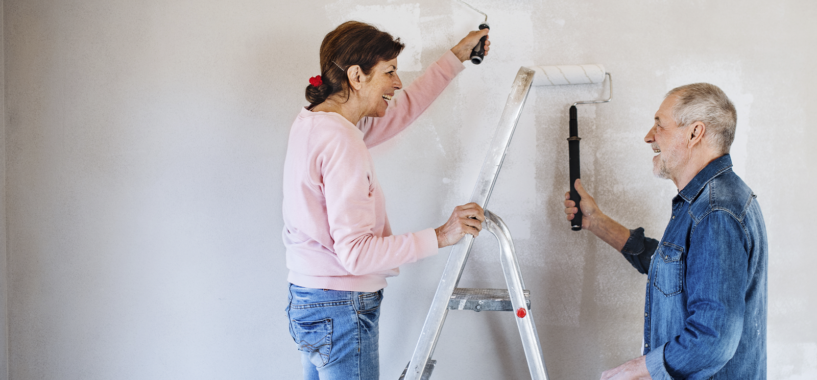 Older couple renovating wall with white paint