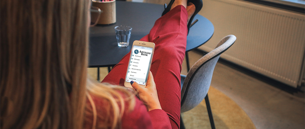Woman with her feet up on a table in a red suit on a phone using AB app