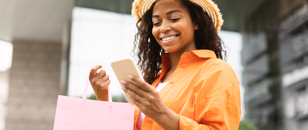 Woman in orange shirt shopping and using cell phone